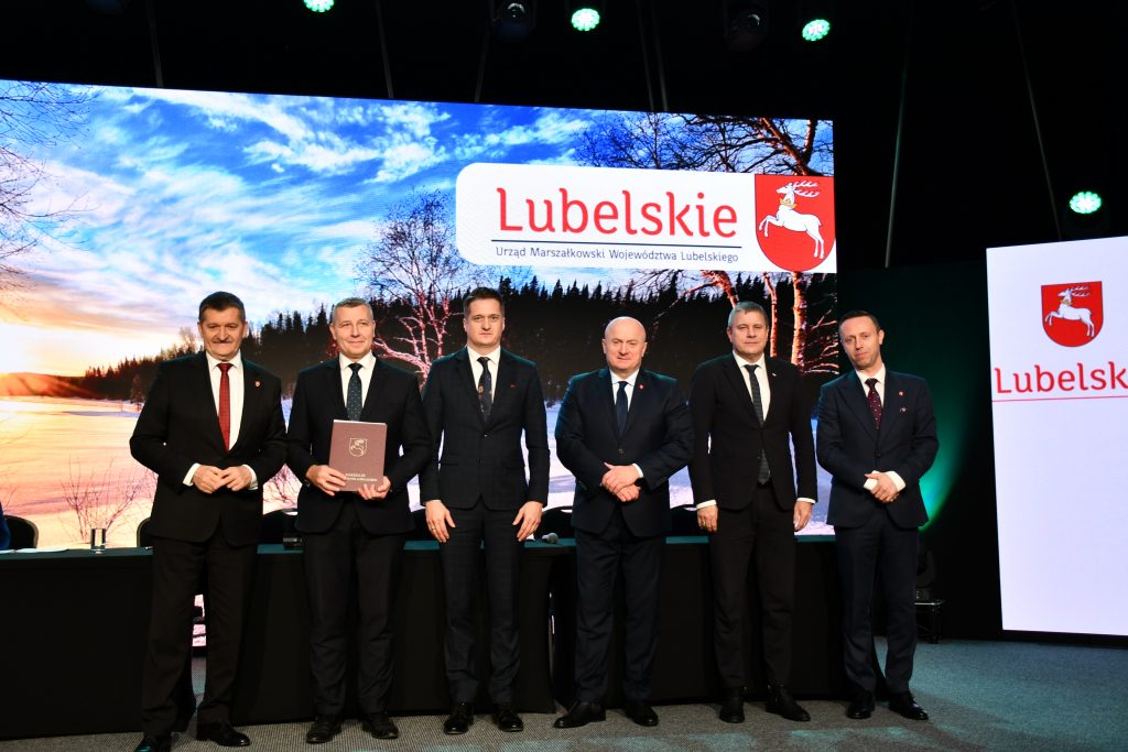 Zdjęcie przedstawia Członków Zarządu Województwa Lubelskiego wraz z przedstawicielem Lokalnej Grupy Działania podczas podpisania umowy. Pięciu mężczyzn w czarnych garniturach.