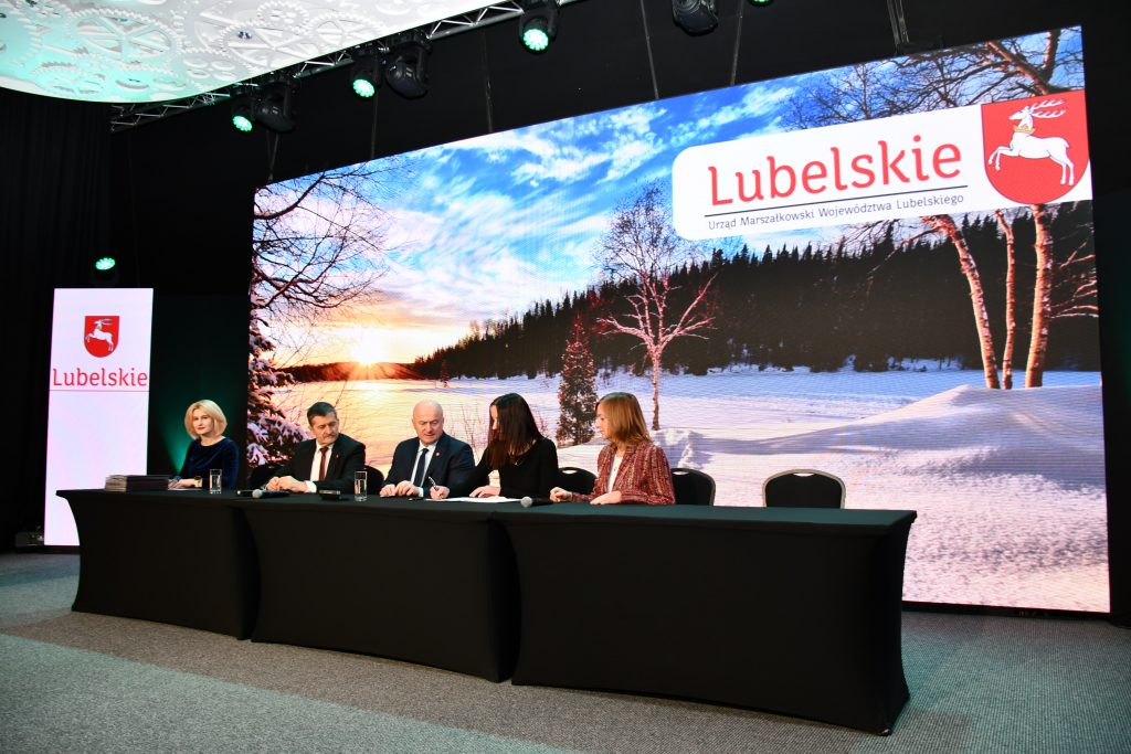 Zdjęcie przedstawia Członków Zarządu Województwa Lubelskiego wraz z przedstawicielem Lokalnej Grupy Działania podczas podpisania umowy. Trzy kobiety i dwóch mężczyzn ubranych elegancko.