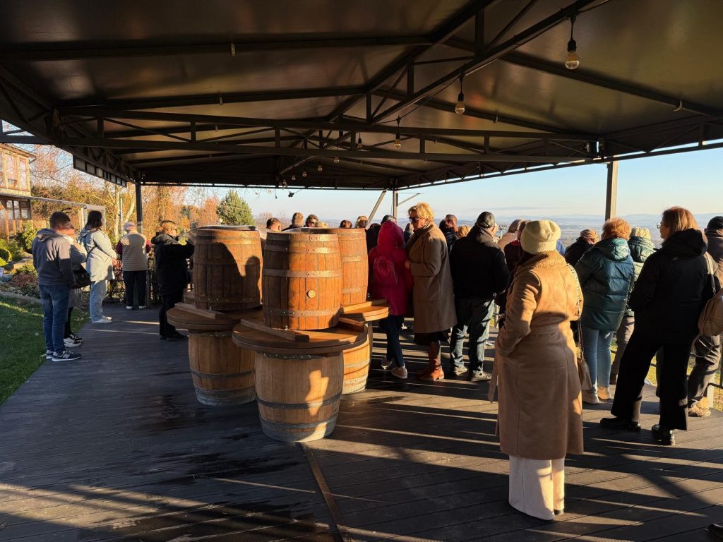 Grupa uczestników wyjazdu studyjnego do województwa podkarpackiego znajduje się w wiacie Winnicy Widokowej, w której ustawione są dębowe beczki na wino