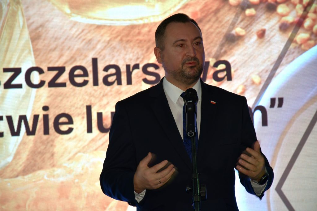 Wicemarszałek Marek Wojciechowski mówi do mikrofonu podczas konferencji „Wsparcie pszczelarstwa w województwie lubelskim. Jest to ujęcie pokazujące sylwetkę do pasa.