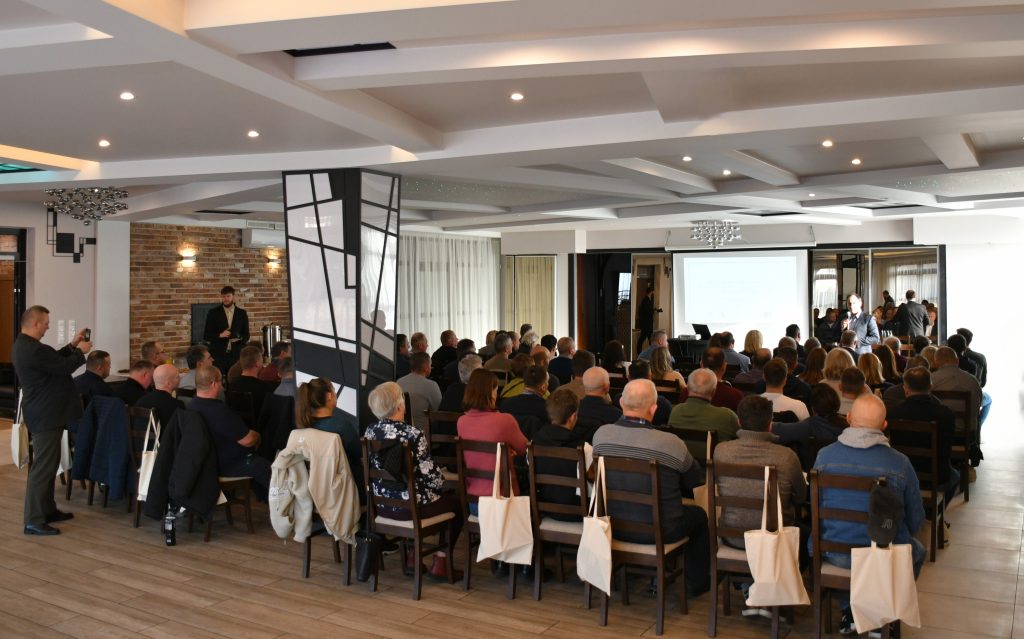 Duża grupa osób siedząca tyłem w Sali konferencyjnej.