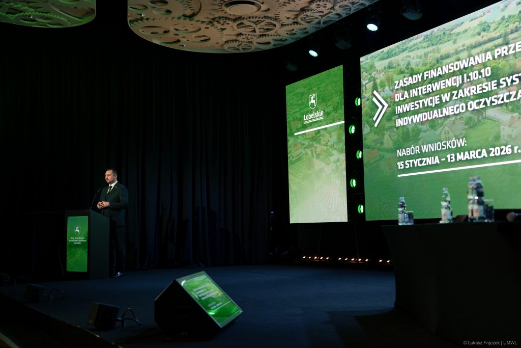 Wicemarszałek Województwa Lubelskiego Marek Wojciechowski mówiący do mikrofonu stojąc za mównicą. W tle ekran wyświetlający napis Lubelskie oraz nabór wniosków od 15 stycznia do 13 marca 2026 r.