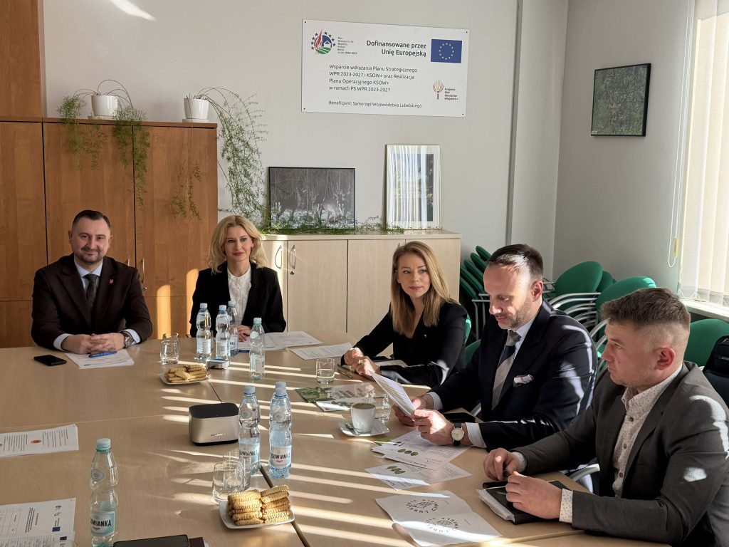 Członkowie Grupy Tematycznej do spraw chmielu elegancko ubrani siedzący przy stole. na stole dokumenty oraz butelki wody.