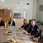 Członkowie Grupy Tematycznej do spraw chmielu elegancko ubrani siedzący przy stole. na stole dokumenty oraz butelki wody.