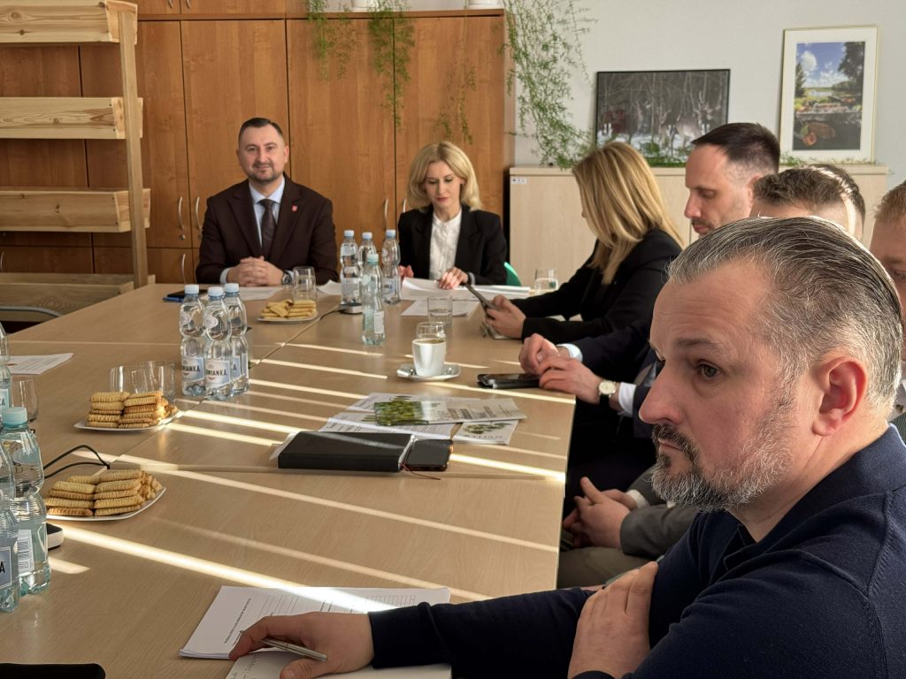 Członkowie Grupy Tematycznej do spraw chmielu elegancko ubrani siedzący przy stole. Mężczyźni oraz kobiety notujący na dokumentacji.