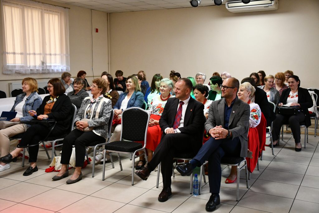 Uczestnicy biorący udział w szkoleniu siedzą w rzędach na krzesłach w sali konferencyjnej z uwagą słuchają prelekcji.