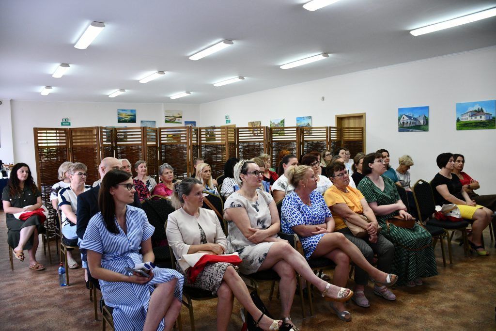 Kobiety biorące udział w szkoleniu siedzą w rzędach na krzesłach w sali konferencyjnej z uwagą słuchają prelekcji.